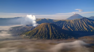 Morning view of Mount Bromo, Mount Batok, and Mount Semeru with mist and volcanic smoke in East Java, Indonesia.