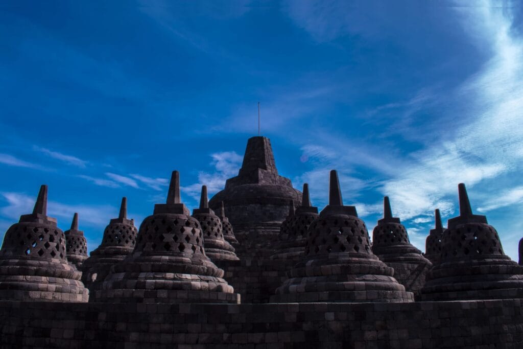Borobudur Temple under a bright blue sky, showcasing the ancient Buddhist architecture and spiritual beauty admired during a Trip to Yogyakarta.
