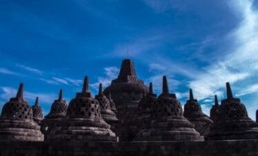 Borobudur Temple under a bright blue sky, showcasing the ancient Buddhist architecture and spiritual beauty admired during a Trip to Yogyakarta.