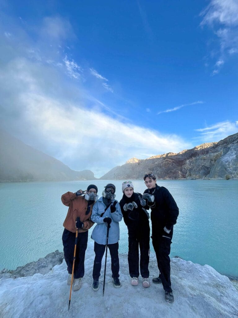 Four hikers in gas masks pose by Ijen Crater Lake after viewing the Ijen sunrise & Blue Flame.