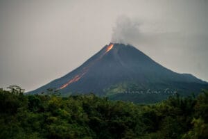 Glowing lava flow from Mount Merapi during night eruption, illuminating the dark sky in Yogyakarta, Indonesia