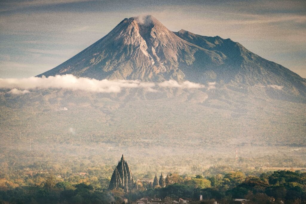 Majestic view of Mount Merapi towering over Prambanan Temple, capturing the natural and cultural beauty experienced during a Trip to Yogyakarta.