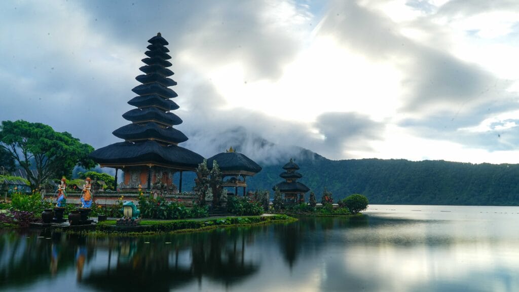 Beautiful view of Ulun Danu Beratan Temple surrounded by misty mountains and calm lake waters.