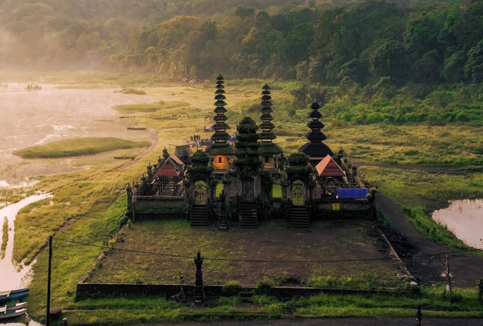 Scenic view of Ulun Danu Tamblingan Temple surrounded by misty hills and calm lake waters in Bali
