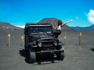 against the volcanic landscape of Mount Bromo under a clear blue sky, showcasing the stunning afternoon panorama Bromo with mountain views and open desert scenery.