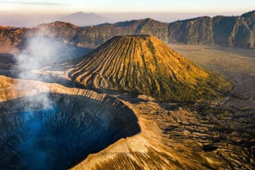 Aerial view of Mount Bromo’s smoking crater and Mount Batok’s ridged cone, showcasing the dramatic volcanic landscape in the Ring of Fire Indonesia.