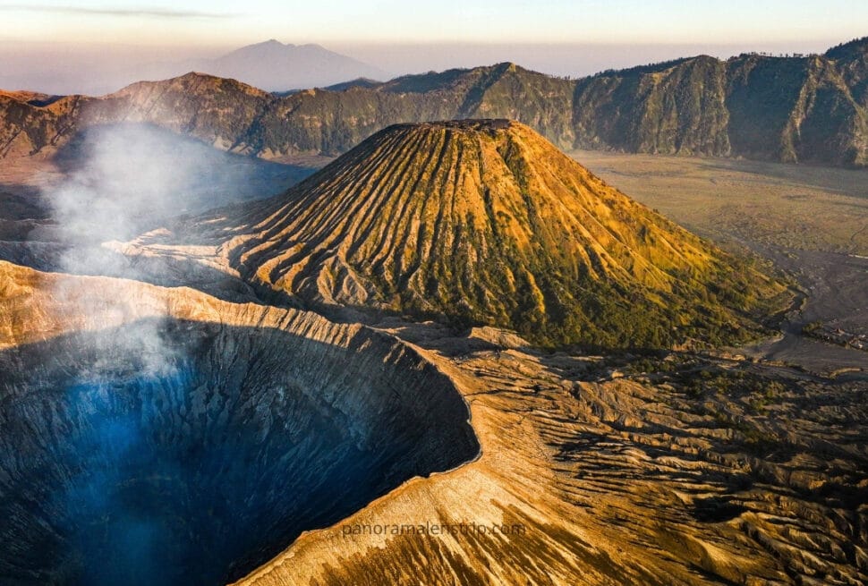 Aerial view of Mount Bromo’s smoking crater and Mount Batok’s ridged cone, showcasing the dramatic volcanic landscape in the Ring of Fire Indonesia.