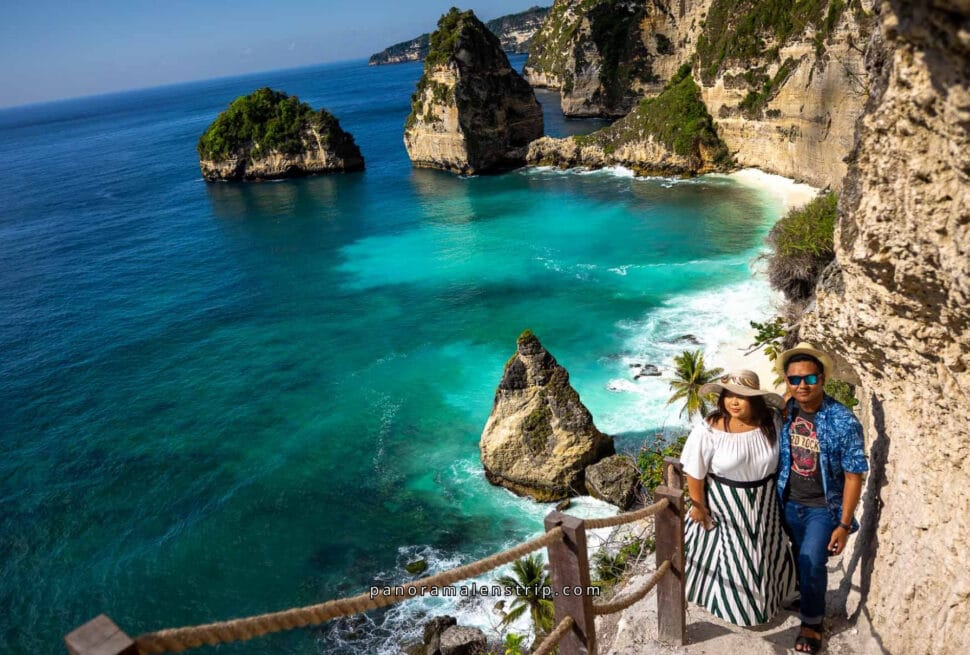 A couple enjoying a scenic cliffside view during their Bali honeymoon, overlooking turquoise waters, dramatic limestone cliffs, and iconic rock formations at a stunning tropical beach.