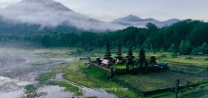 Ulun Danu Beratan water temple in Bali surrounded by misty mountains and green landscape