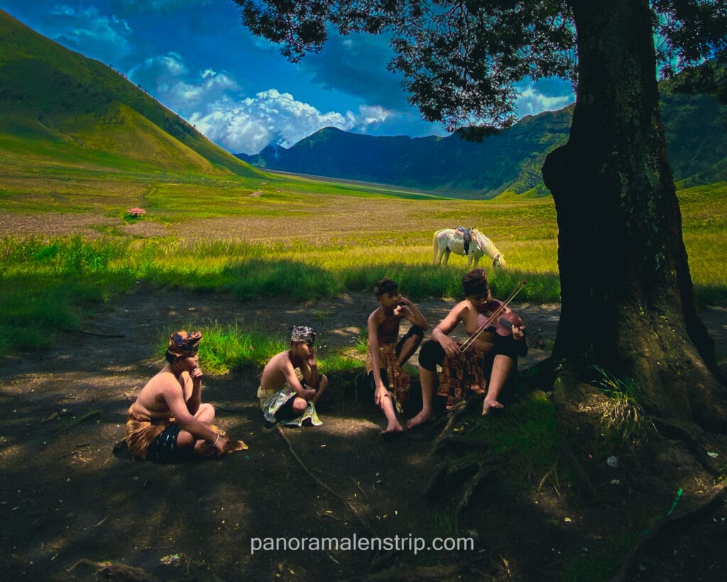 Traditional musicians playing violin in Mount Bromo landscape wearing Tenggerese attire during