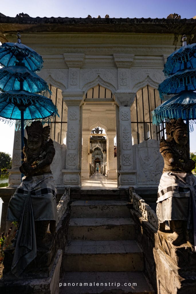 Ujung Palace bridge framed by traditional Balinese temple gates and guardian statues, highlighting cultural architecture and serene water gardens—ideal inspiration for Bali travel tips and tricks when visiting East Bali.