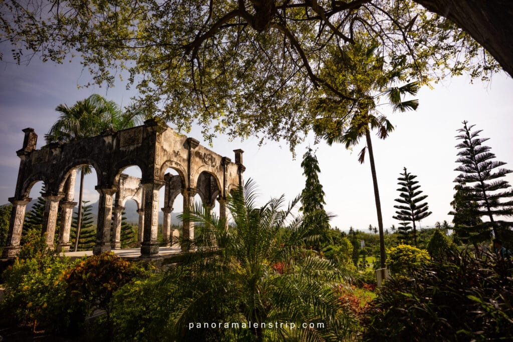 Bali travel tips and tricks illustrated by a historic water palace garden with stone arches and tropical trees in East Bali