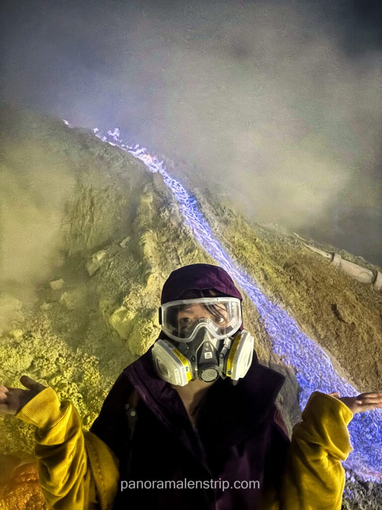 A traveler wearing a protective gas mask and goggles standing in front of the blue fire at Mount Ijen, Indonesia.