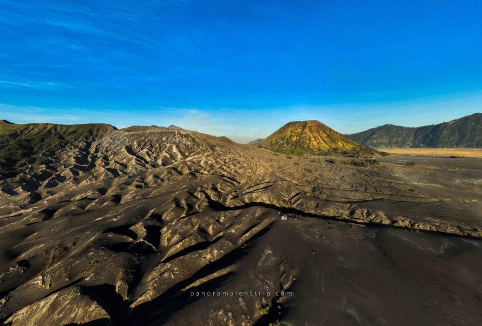 A stunning aerial view of Mount Bromo’s crater surrounded by misty mountains at sunrise, capturing the breathtaking beauty of a Bromo Trip in East Java, Indonesia.