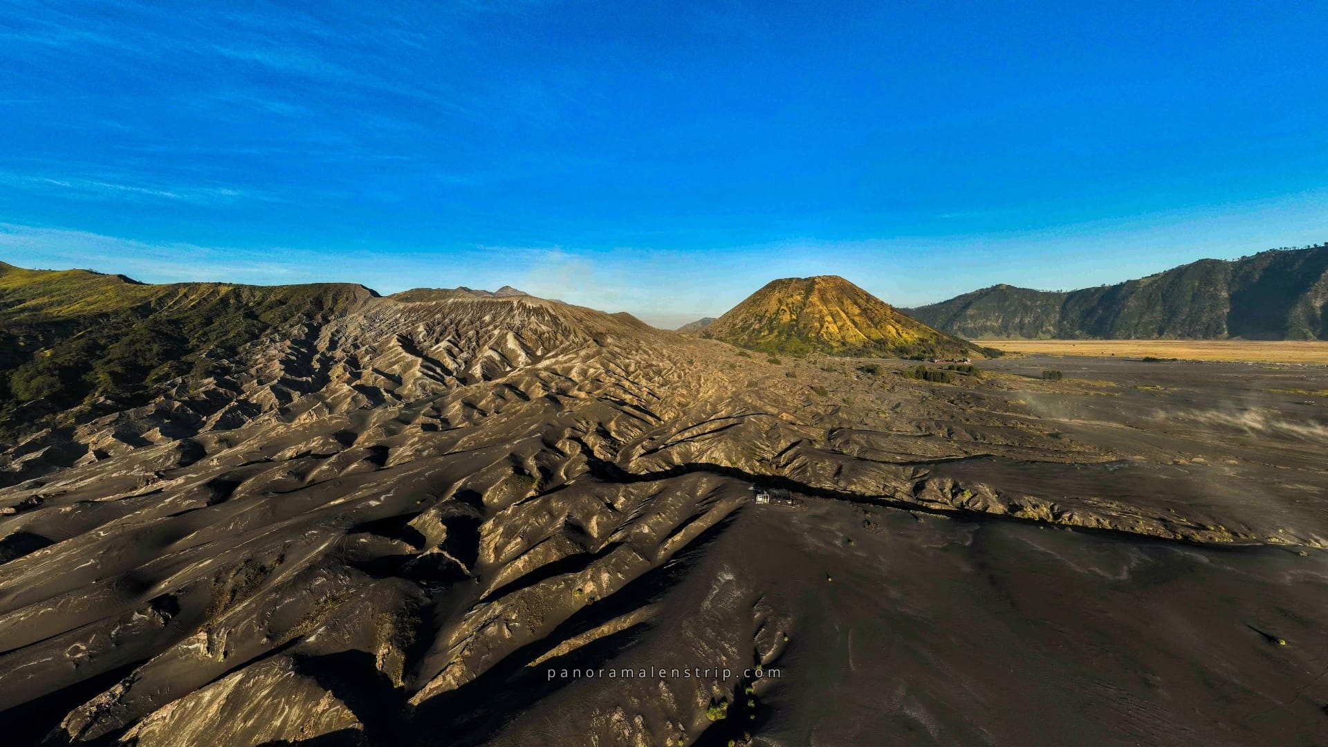 A stunning aerial view of Mount Bromo’s crater surrounded by misty mountains at sunrise, capturing the breathtaking beauty of a Bromo Trip in East Java, Indonesia.