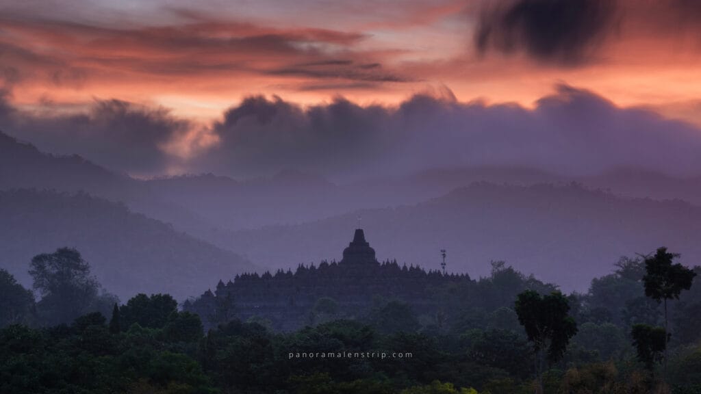 Borobudur sunrise view with misty hills and dramatic clouds, revealing the temple silhouette at dawn in Central Java, Indonesia.