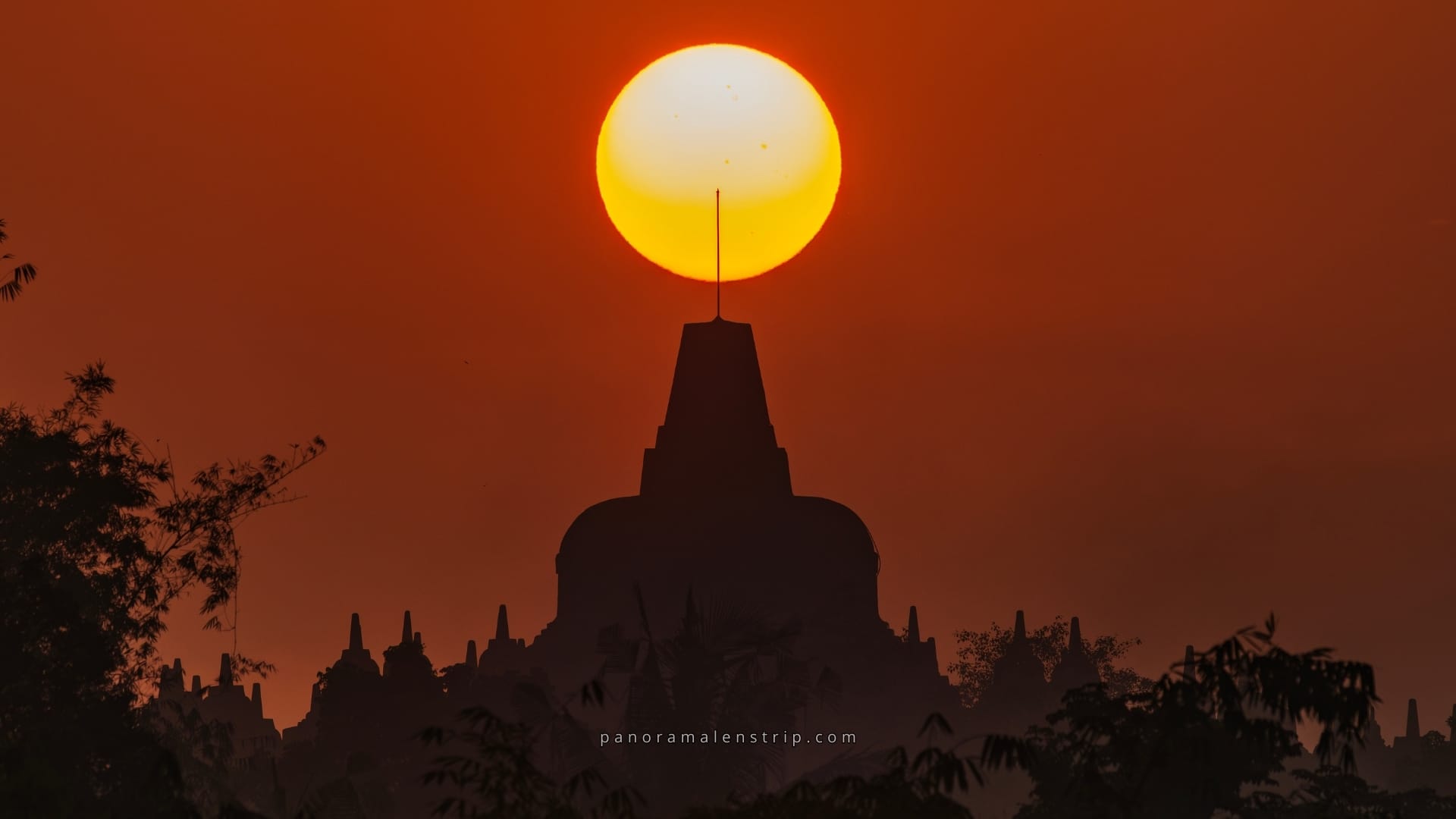 Borobudur sunrise view with the glowing sun perfectly aligned above the main stupa, creating a dramatic silhouette of Borobudur Temple at dawn in Indonesia.