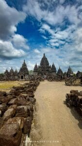 History of Prambanan Temple seen from the main pathway leading to the central Shiva shrine under a dramatic sky in Central Java, Indonesia.