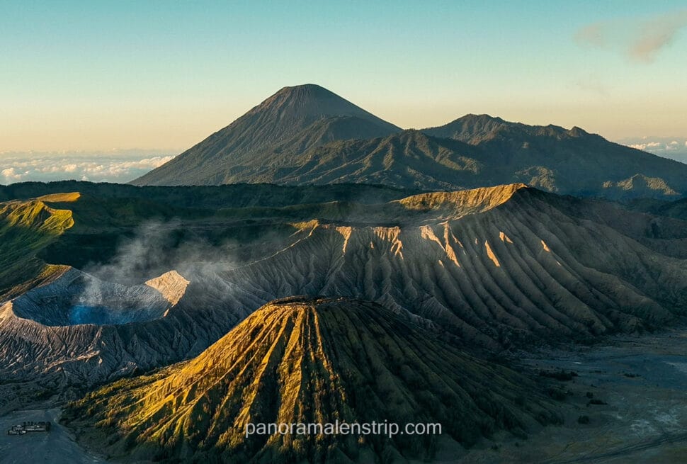 Classic sunrise view of Mount Batok, Mount Bromo, and Mount Semeru erupting in the background from King Kong Hill viewpoint.