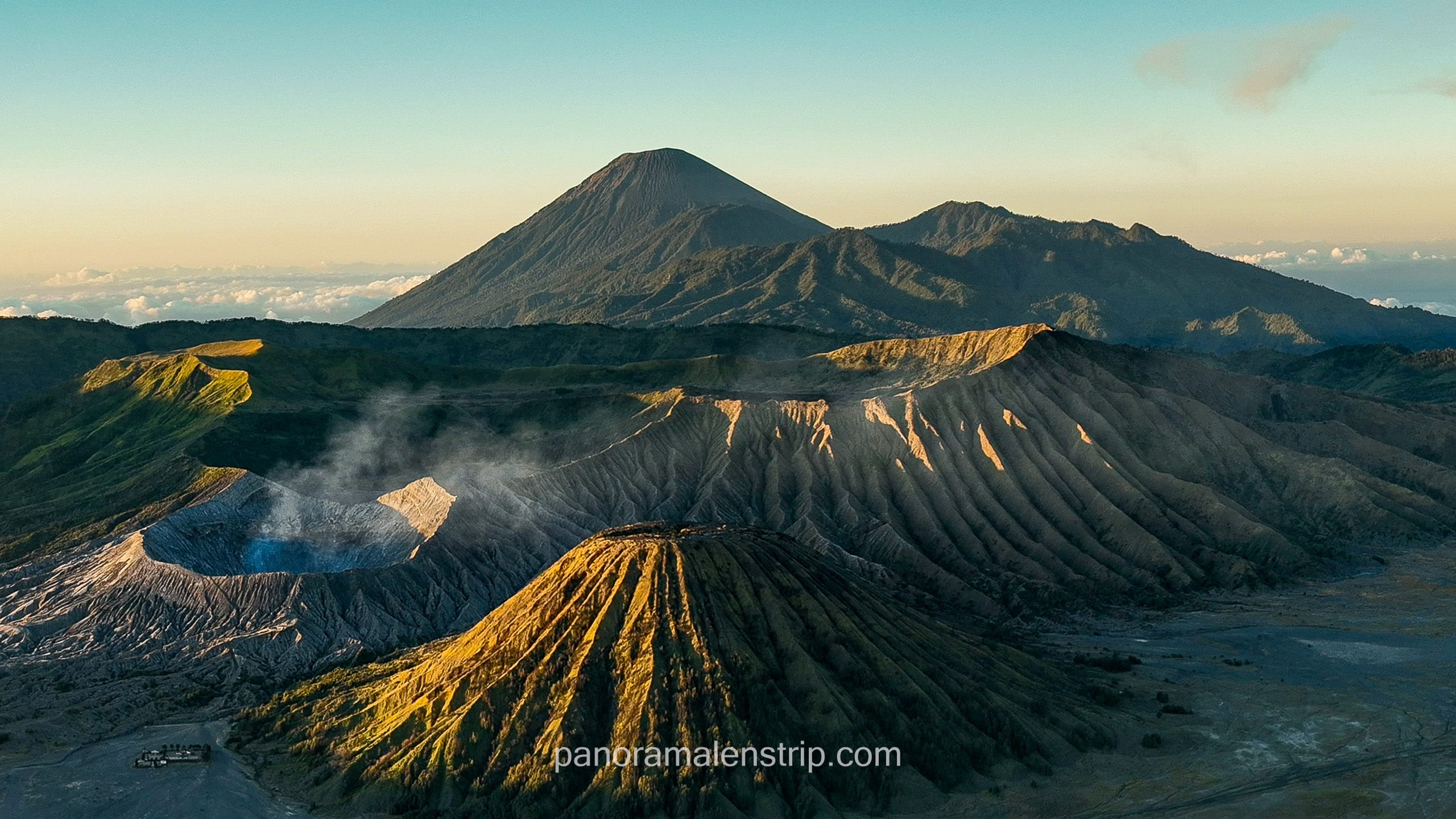 Classic sunrise view of Mount Batok, Mount Bromo, and Mount Semeru erupting in the background from King Kong Hill viewpoint.