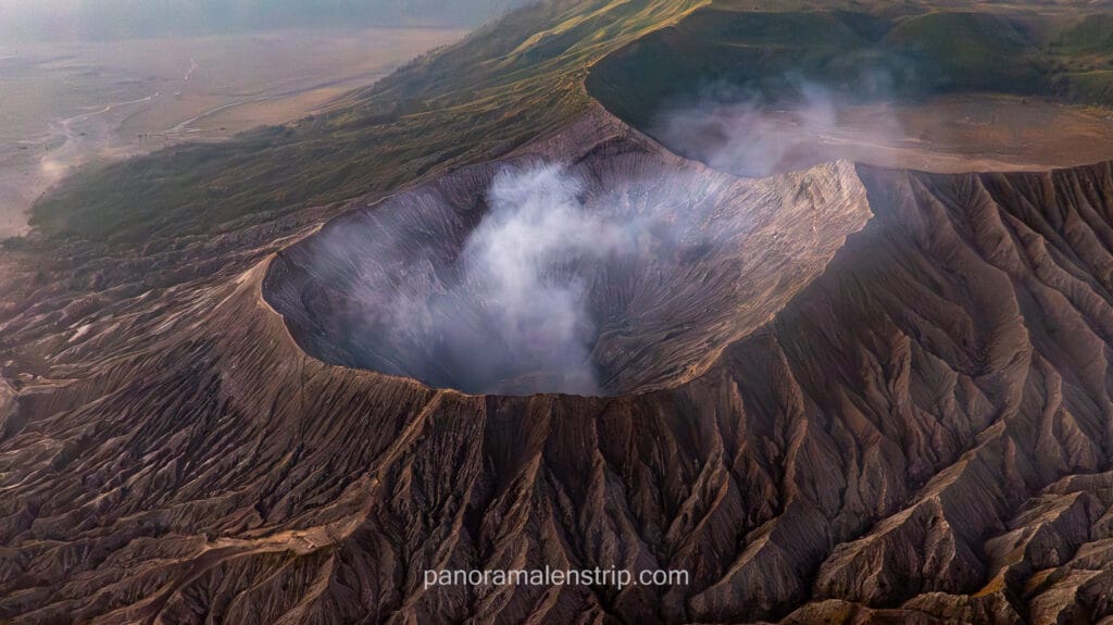 High-angle drone view looking directly into the smoking sulfur crater of Mount Bromo.