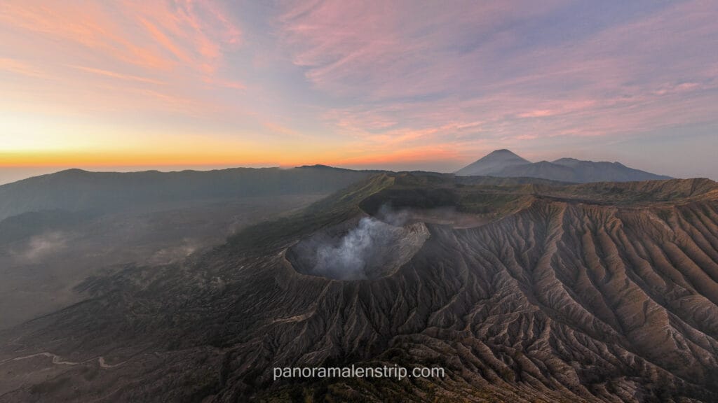 Vibrant pink and orange sunrise clouds over Mount Bromo and the caldera landscape.