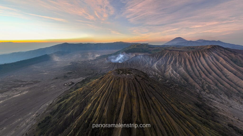 Wide angle shot of Mount Batok and Mount Bromo with Mount Semeru in the distance under morning sky.