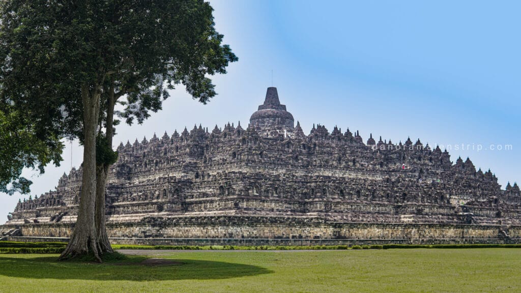 Borobudur sunrise tour view showing the majestic stone structure of Borobudur Temple from the temple yard. Capturing the iconic UNESCO World Heritage monument against a clear blue sky in Yogyakarta, Indonesia.