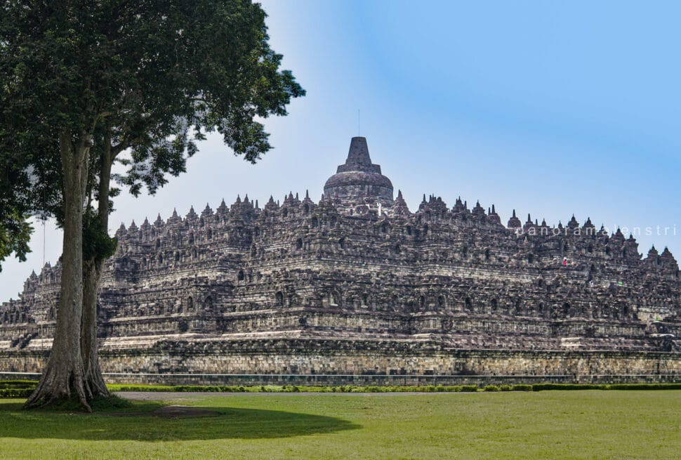 Borobudur sunrise tour view showing the majestic stone structure of Borobudur Temple from the temple yard. Capturing the iconic UNESCO World Heritage monument against a clear blue sky in Yogyakarta, Indonesia.