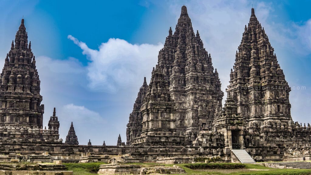 Towering spires of Prambanan Temple rising against a bright blue sky with soft clouds in Yogyakarta, Indonesia