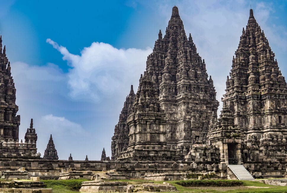 Towering spires of Prambanan Temple rising against a bright blue sky with soft clouds in Yogyakarta, Indonesia
