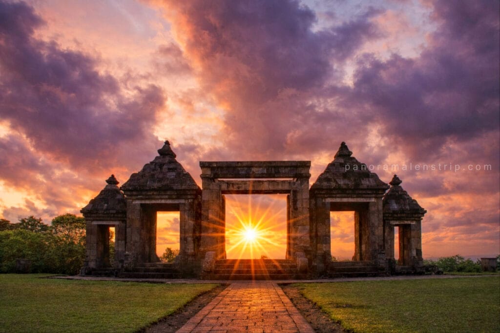 Sunset view through the ancient stone gate of Ratu Boko Temple with dramatic clouds and golden sunlight, highlighting a scenic Ratu Boko tour in Yogyakarta, Indonesia.
