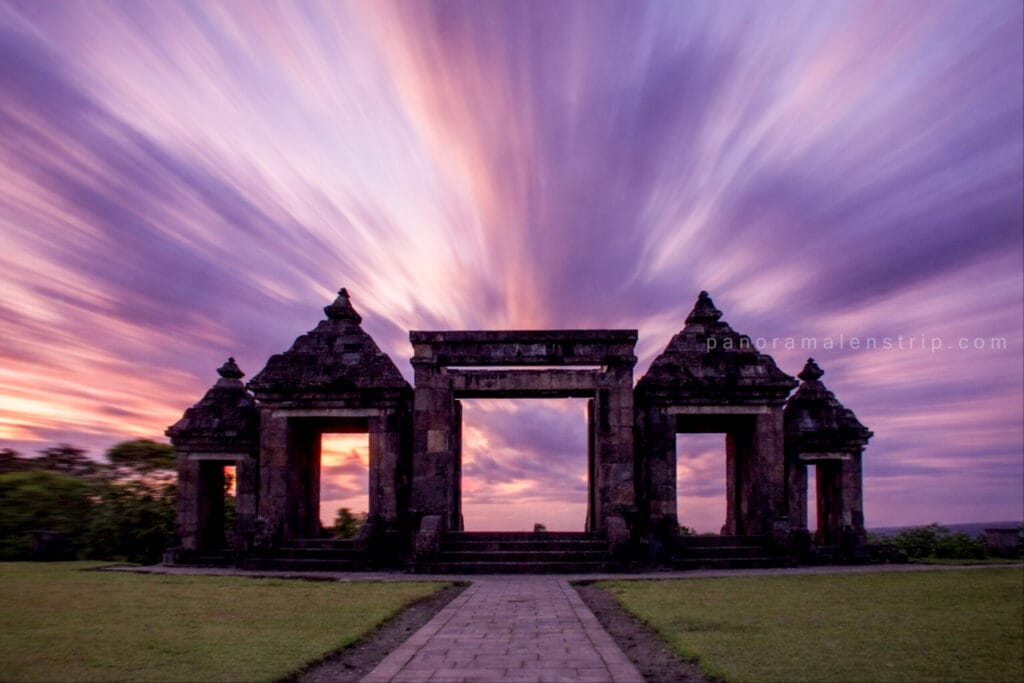 Ancient stone gates of Ratu Boko Temple under a dramatic purple twilight sky with long-exposure clouds, showcasing a serene Ratu Boko tour experience in Yogyakarta.