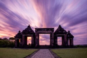 Ancient stone gates of Ratu Boko Temple under a dramatic purple twilight sky with long-exposure clouds, showcasing a serene Ratu Boko tour experience in Yogyakarta.