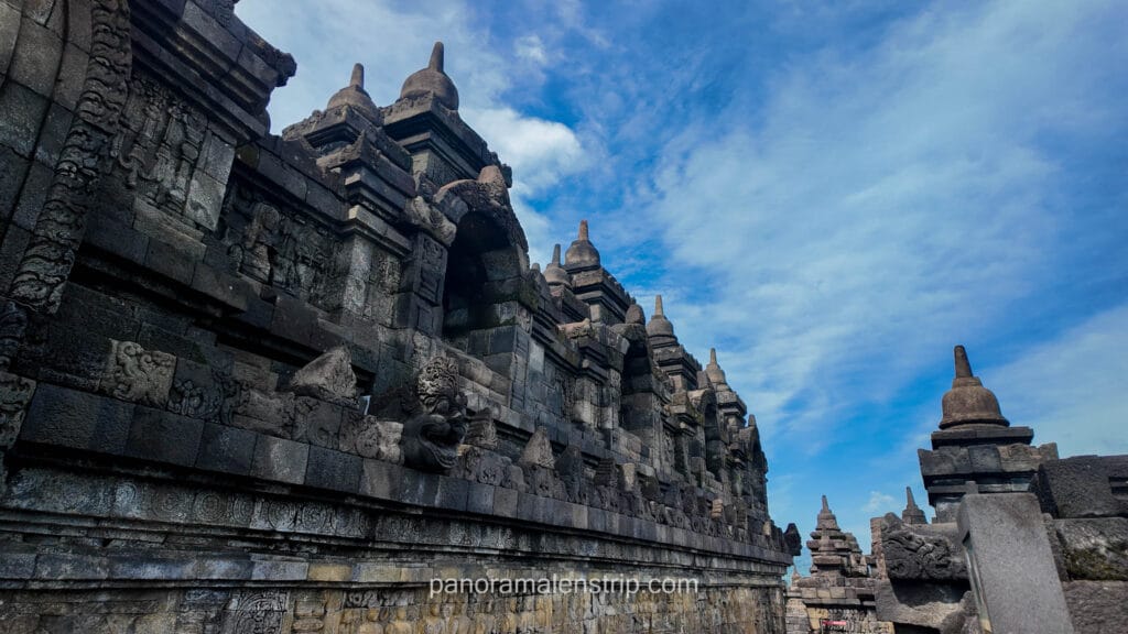 Detailed view of the stone walls and bell-shaped stupas on the upper terraces of Borobudur Temple.