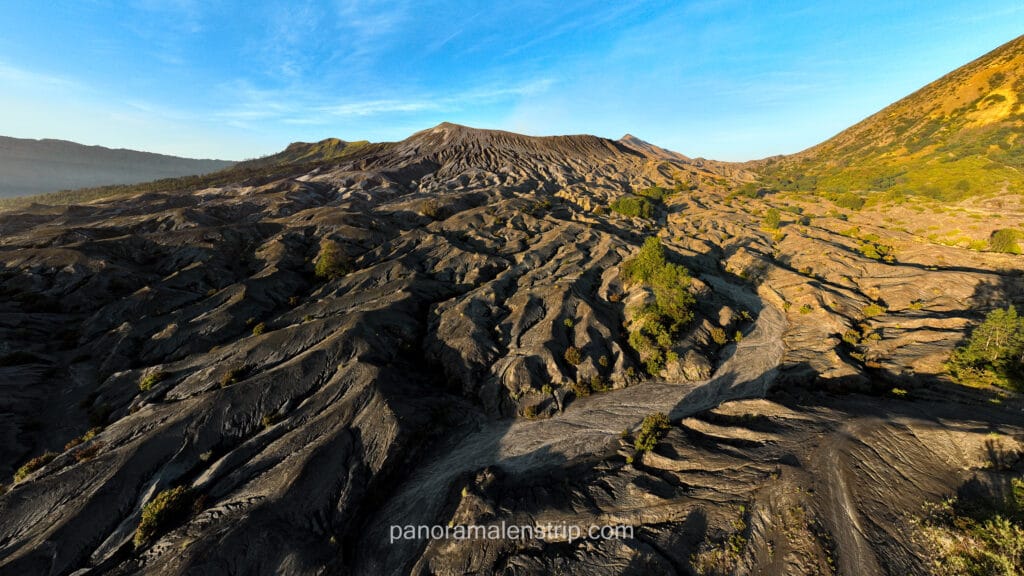 High angle view showing the intricate erosion patterns and volcanic ridges of Mount Bromo's landscape during the morning golden hour.