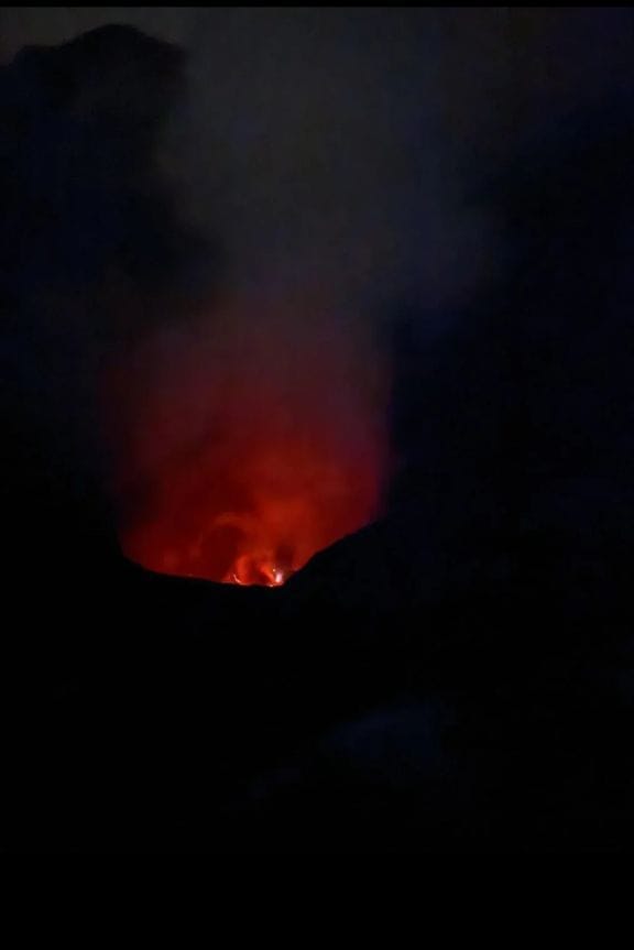 Dramatic night shot of Mount Bromo volcano crater in Indonesia with glowing red lava, fire, and luminous smoke