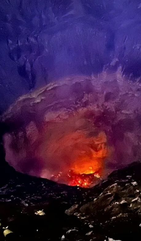 Gunung Bromo volcano erupting at night with vibrant red lava and glowing ash in its crater.