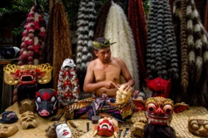 A Balinese mask maker meticulously carving a wooden mask by hand.