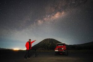 A person posing under the Milky Way with Mount Batok in the background at Bukit Widodaren, Bromo.