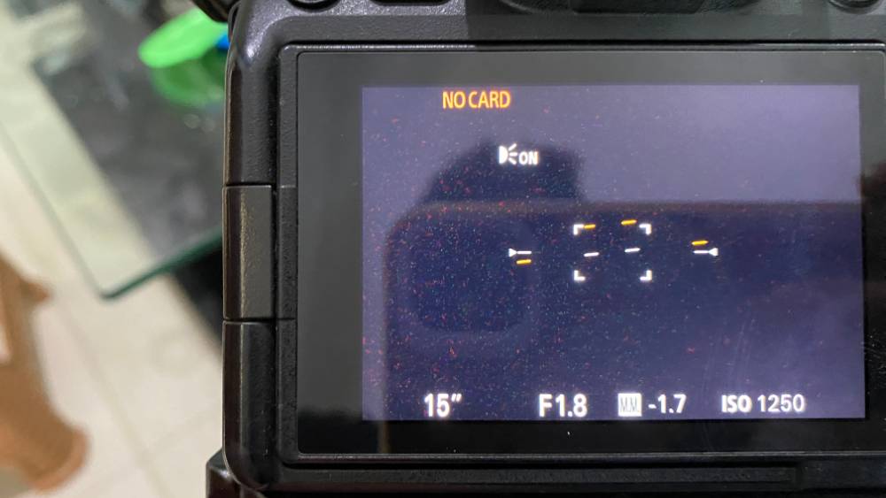 Close-up of a camera LCD screen showing shooting settings and focus points in a travel office setting.