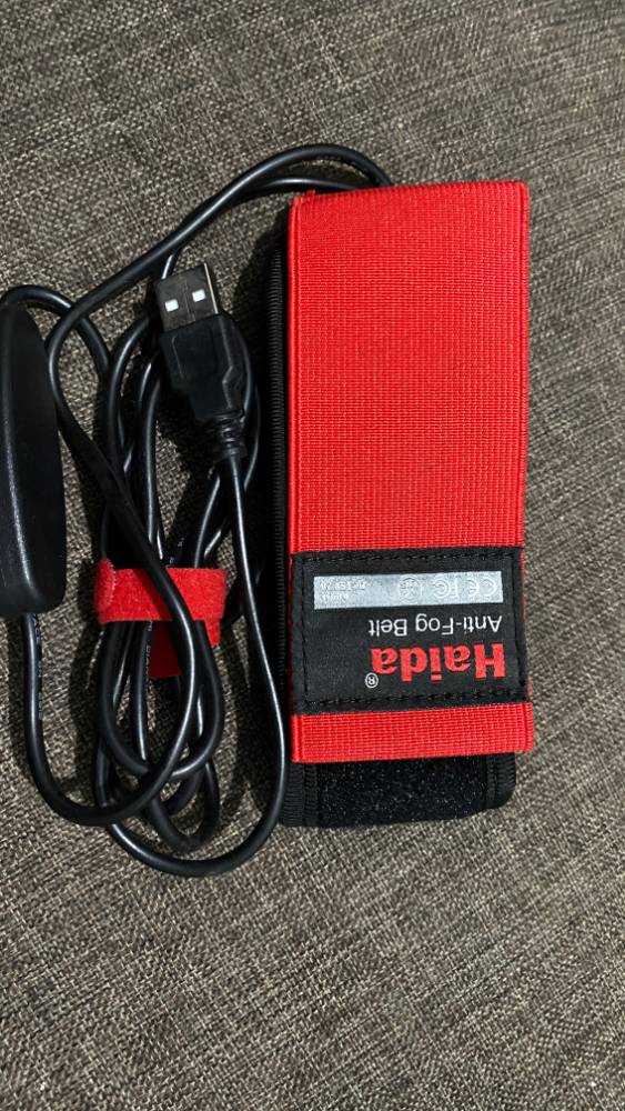 Red and black Hahda anti-fog belt with USB cable on a textured surface