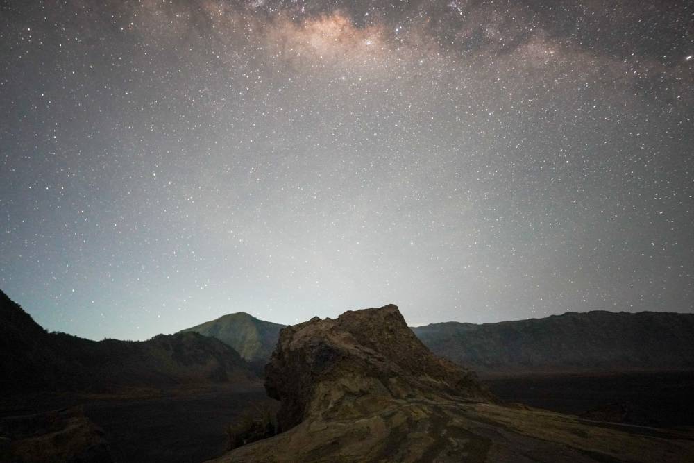 Milky Way over the rocky sand plain of Whispering Sands, Bromo, with a solitary stone in the foreground