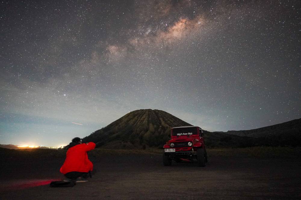 Photographer capturing the Milky Way at Bukit Widodaren in Bromo under a star-filled night sky