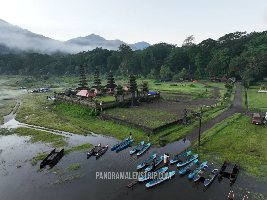 Aerial view of morning ground mist rolling over the pristine waters of Tamblingan Lake during a Bali temple tour.
