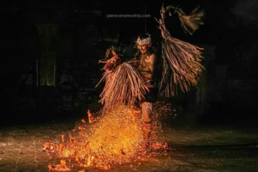 A joyful dancer smiles while dancing over fire with a hobby horse prop.