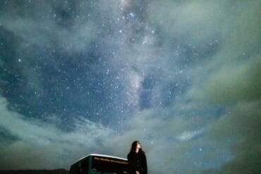 A woman posing on a jeep under a misty Milky Way sky at Pasir Berbisik in May