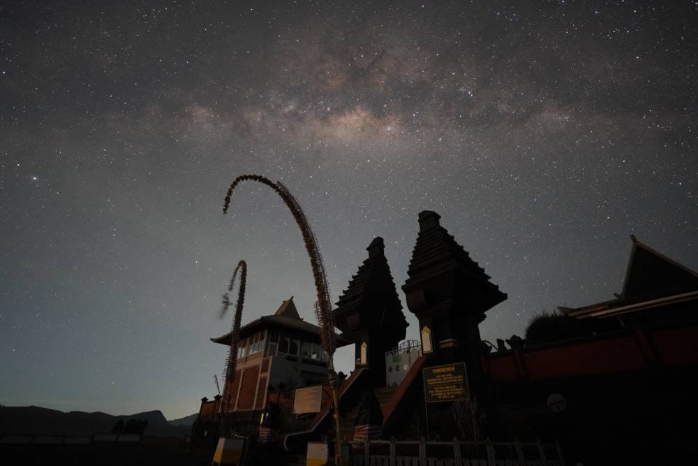 Pura Poten Bromo temple silhouette under a starry night sky with Mount Bromo in the background