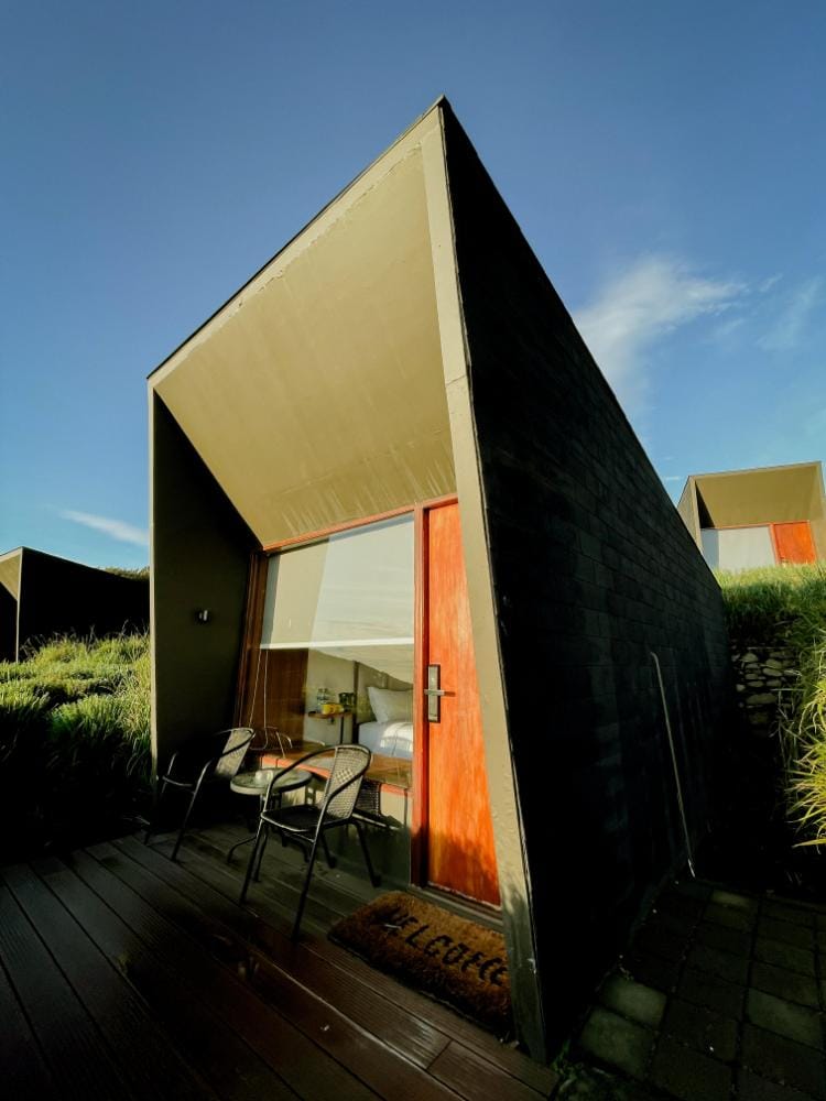 Modern cabin-style hotel room exterior at Artotel Hotel and Cabin Cemaralawang with a private wooden deck and large glass door.