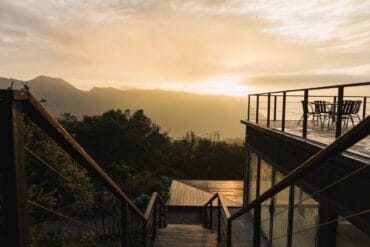 Sunrise view from Artotel restaurant in Cemaralawang Village, overlooking mountain silhouettes and a tranquil terrace